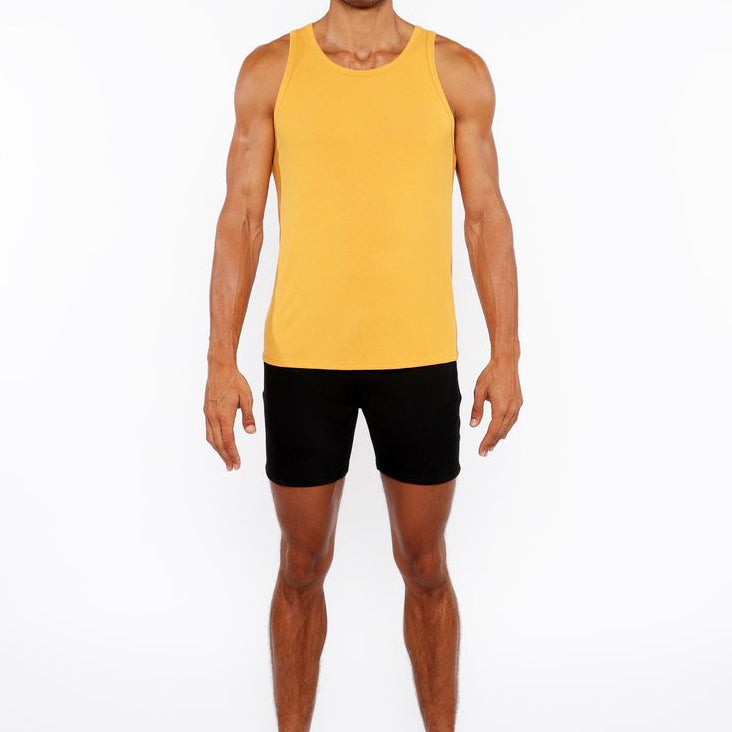 Man wearing a yellow tank top and black shorts on a white background
