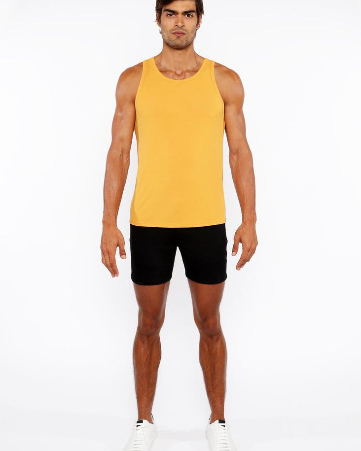 Man wearing a yellow tank top and black shorts on a white background