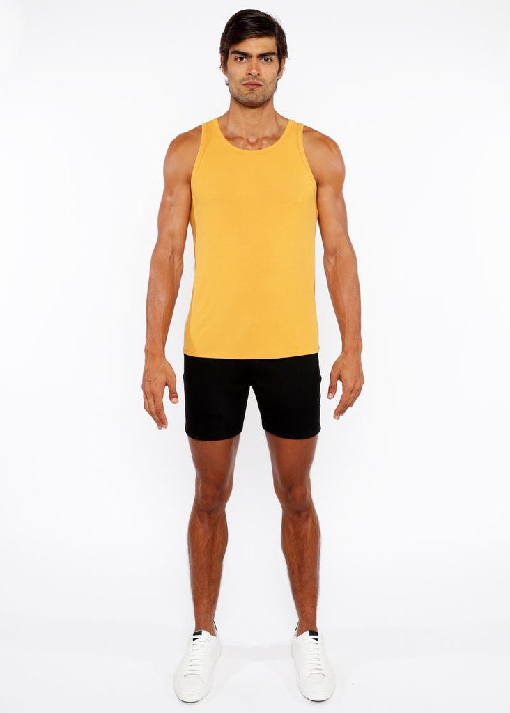 Man wearing a yellow tank top and black shorts on a white background
