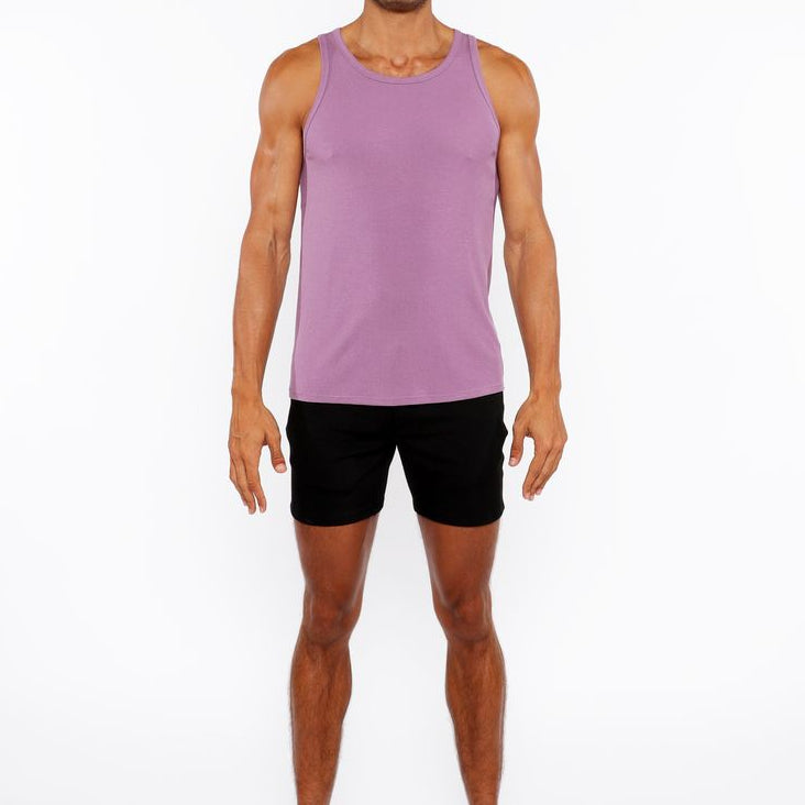Man wearing a purple tank top and black shorts on a white background