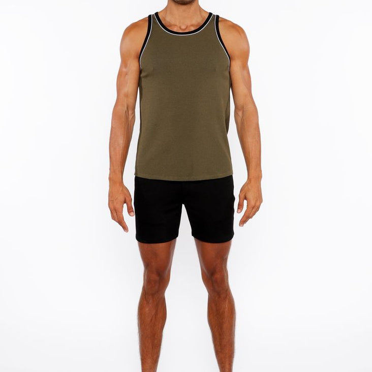 Man wearing an olive green tank top and black shorts on a white background