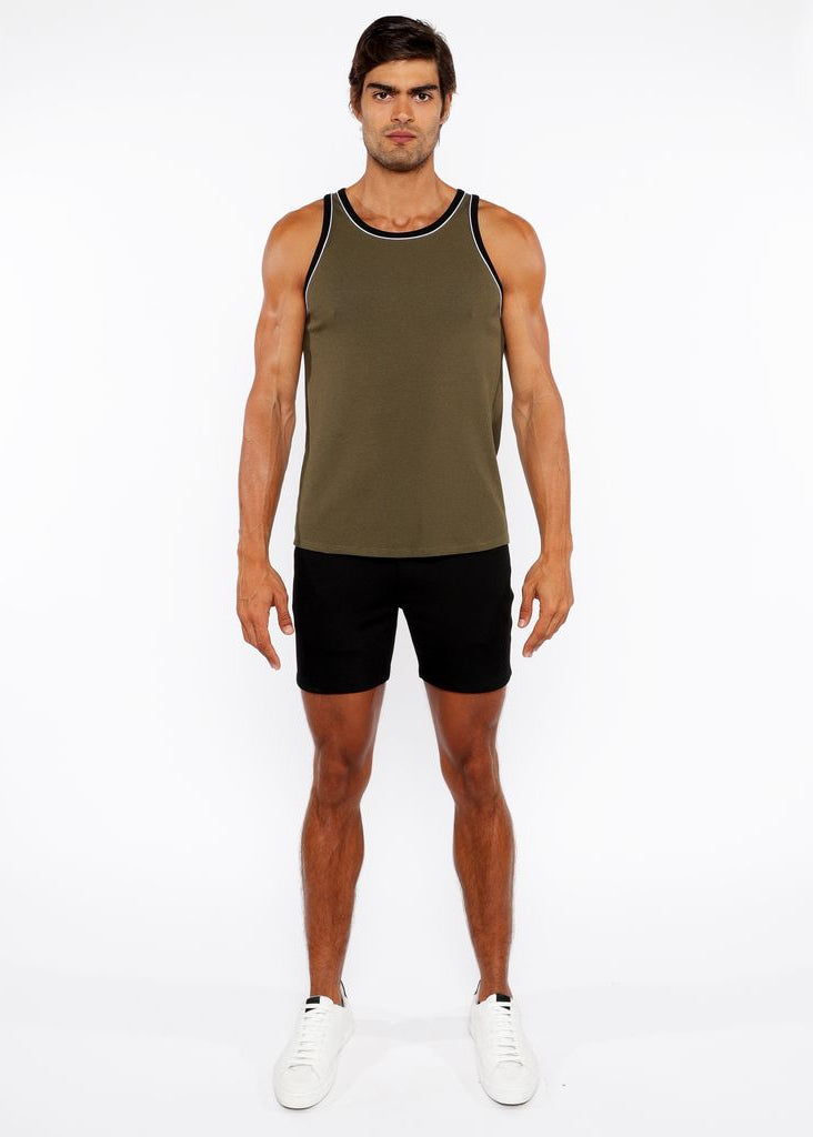 Man wearing an olive green tank top and black shorts on a white background