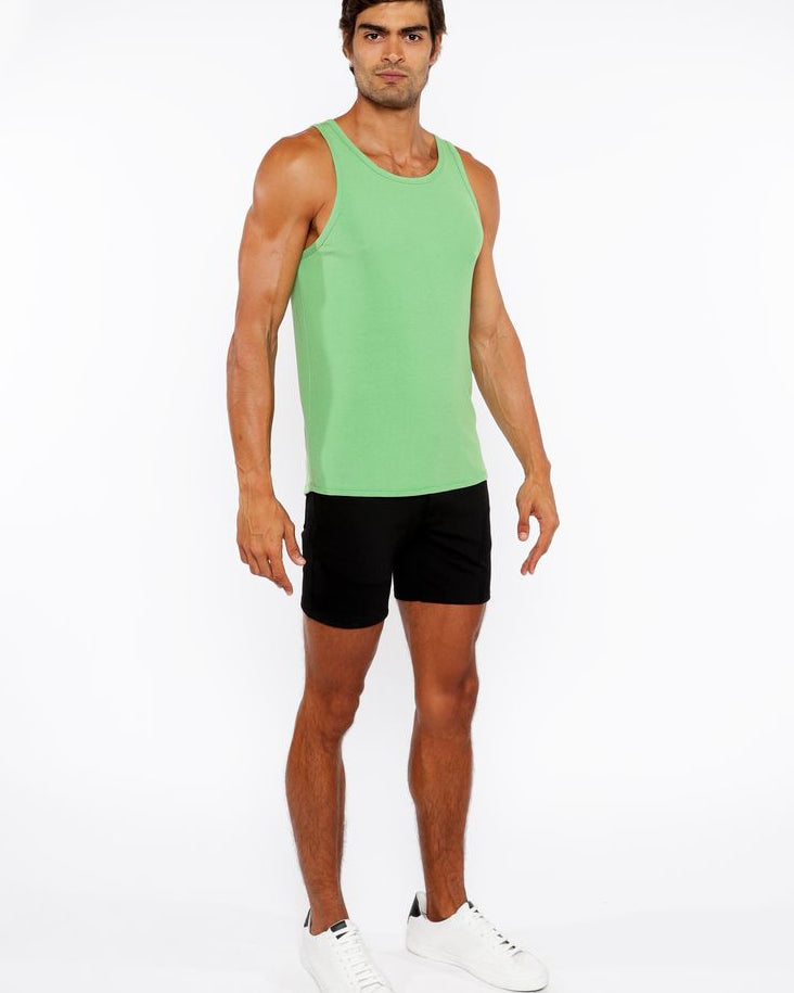 Man wearing a green tank top and black shorts on a white background