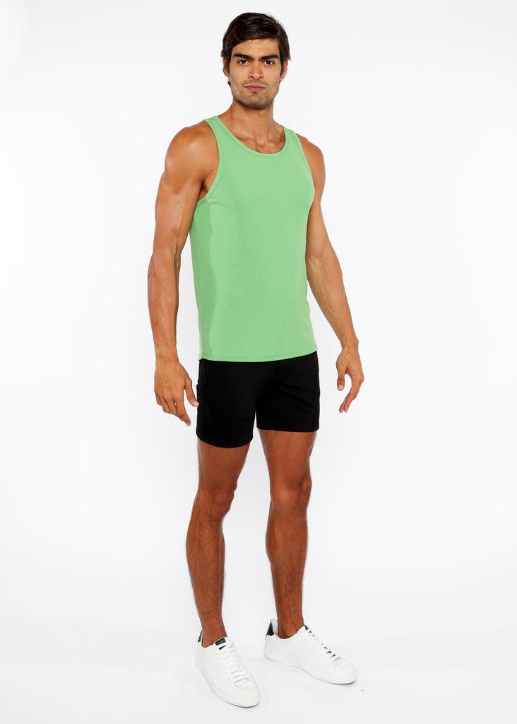 Man wearing a green tank top and black shorts on a white background