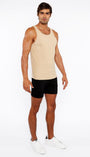 Man wearing a beige tank top and black shorts on a white background