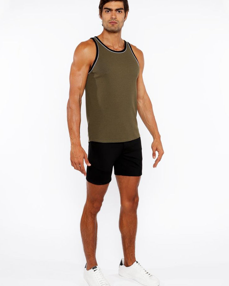 Man wearing a green tank top and black shorts on a white background