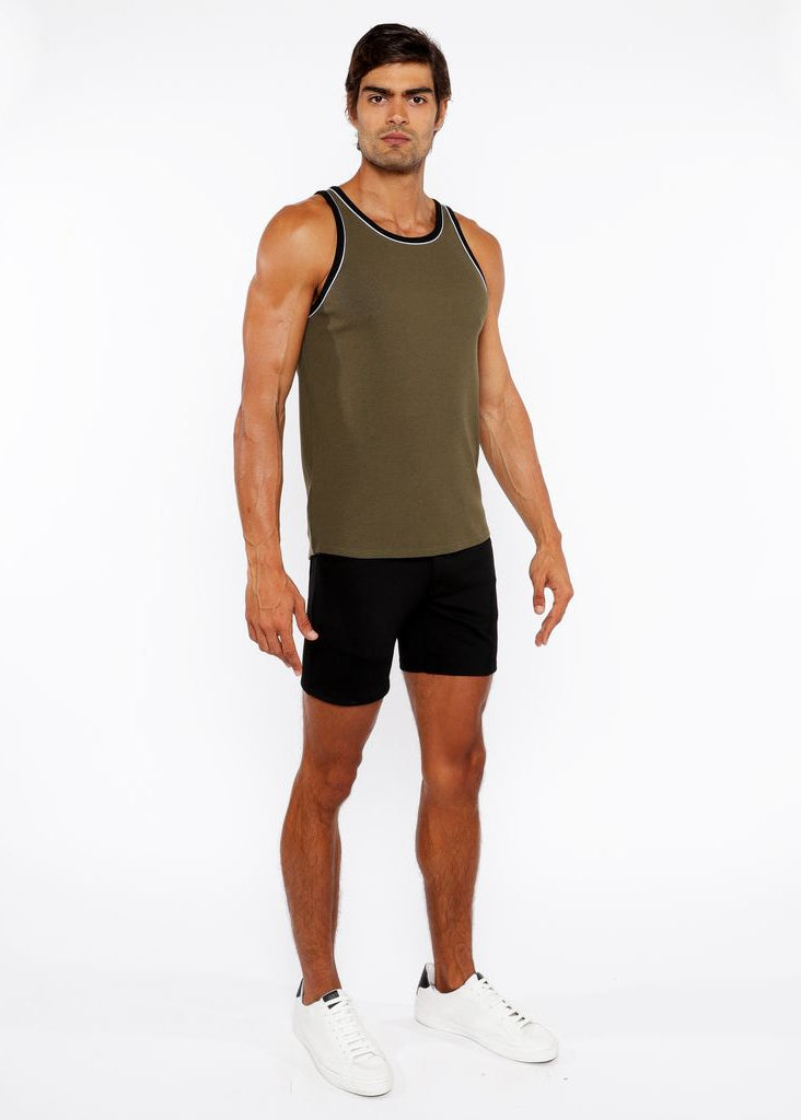 Man wearing a green tank top and black shorts on a white background