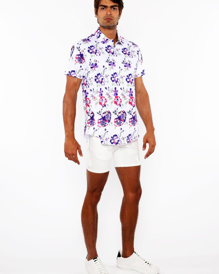 Man wearing a floral shirt and white shorts on a white background