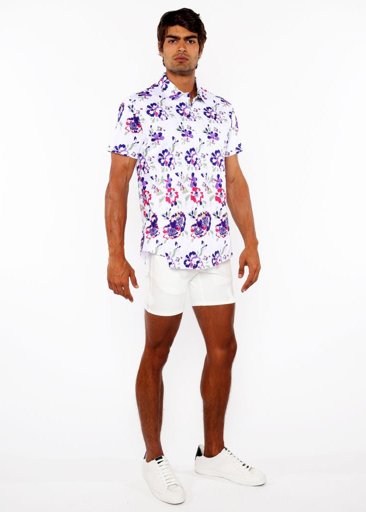Man wearing a floral shirt and white shorts on a white background