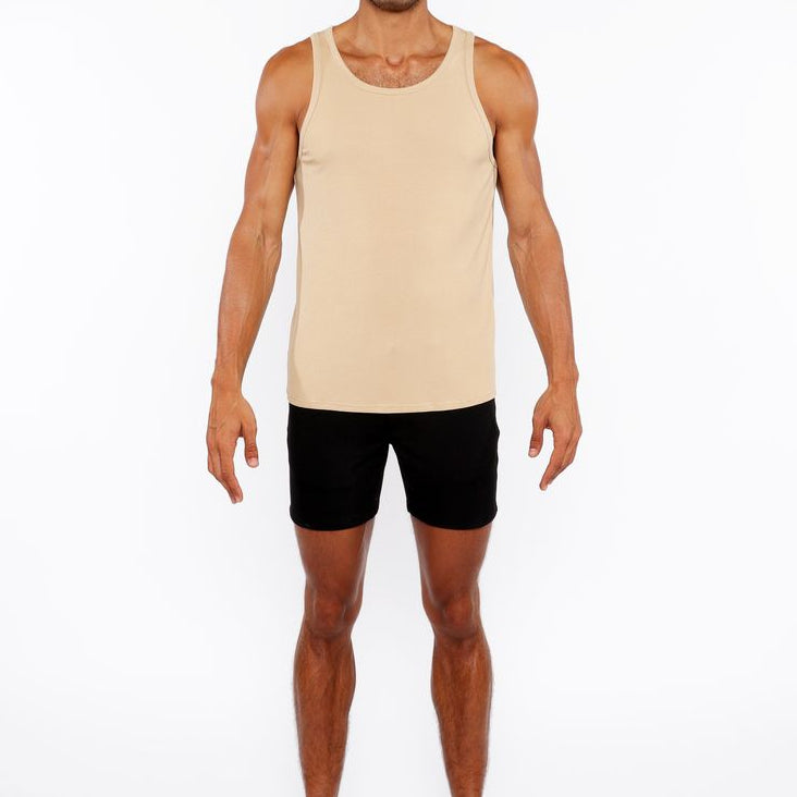 Man wearing a beige tank top and black shorts on a white background