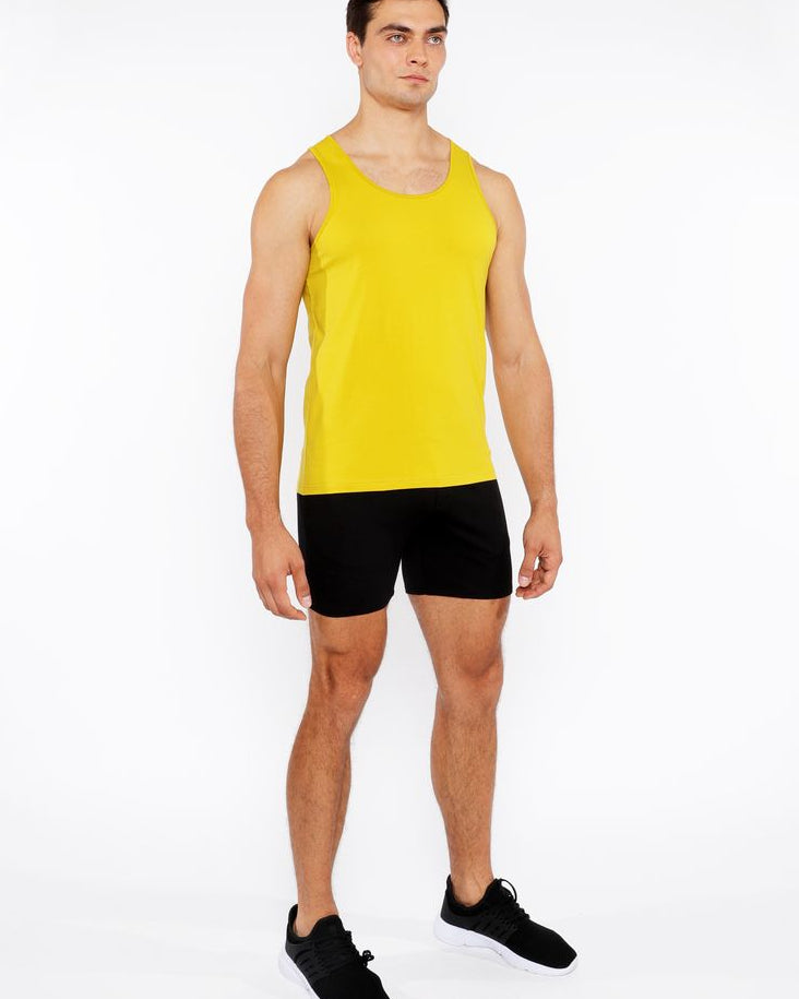 Man wearing a yellow tank top and black shorts on a white background