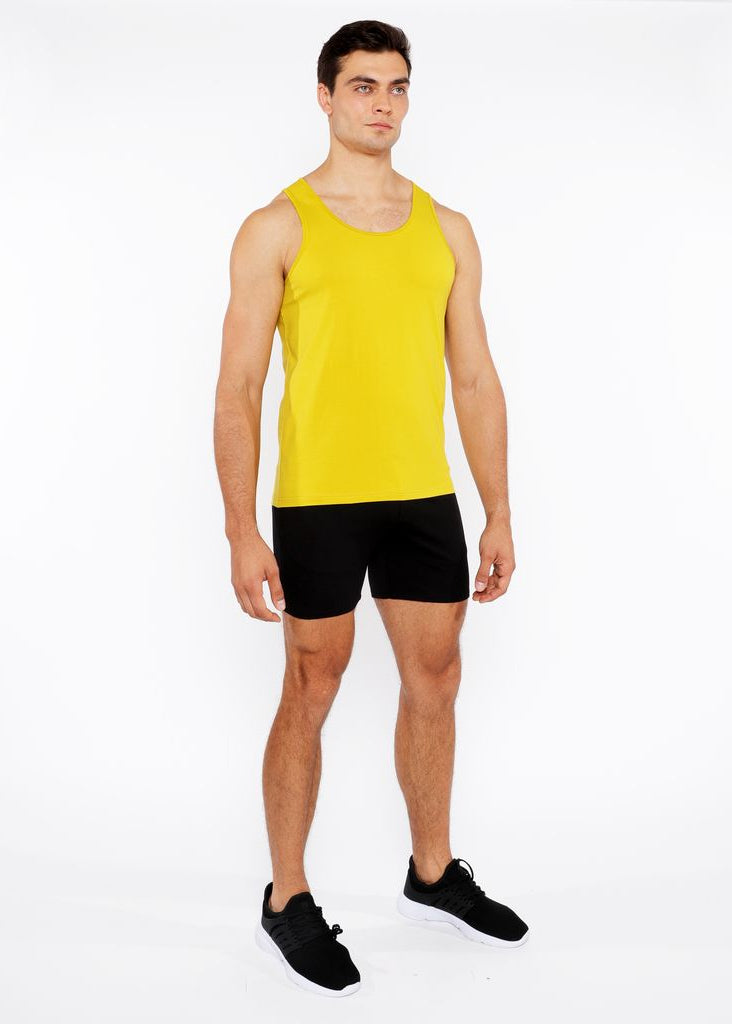 Man wearing a yellow tank top and black shorts on a white background