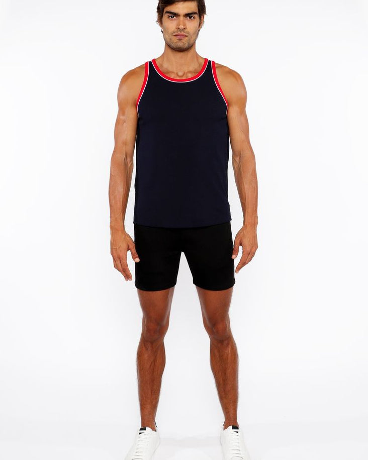 Man wearing a black tank top with red trim and black shorts on a white background