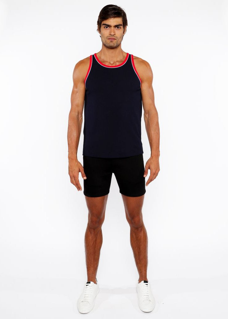 Man wearing a black tank top with red trim and black shorts on a white background