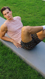 Man stretching on a grassy area next to a sidewalk