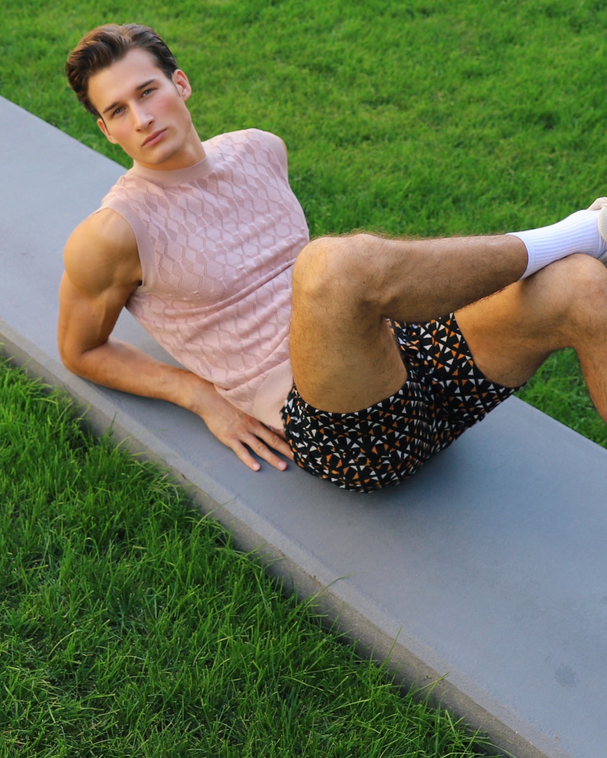 Man stretching on a grassy area next to a sidewalk