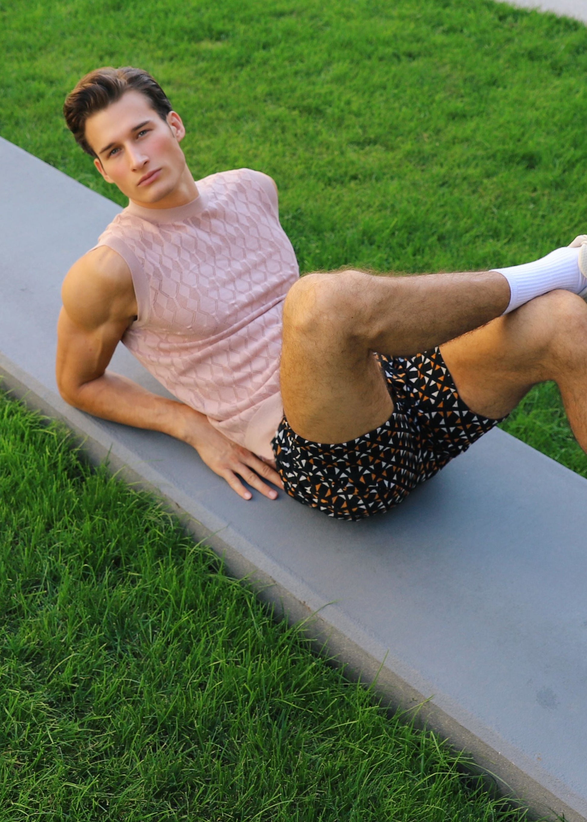 Man stretching on a grassy area next to a sidewalk