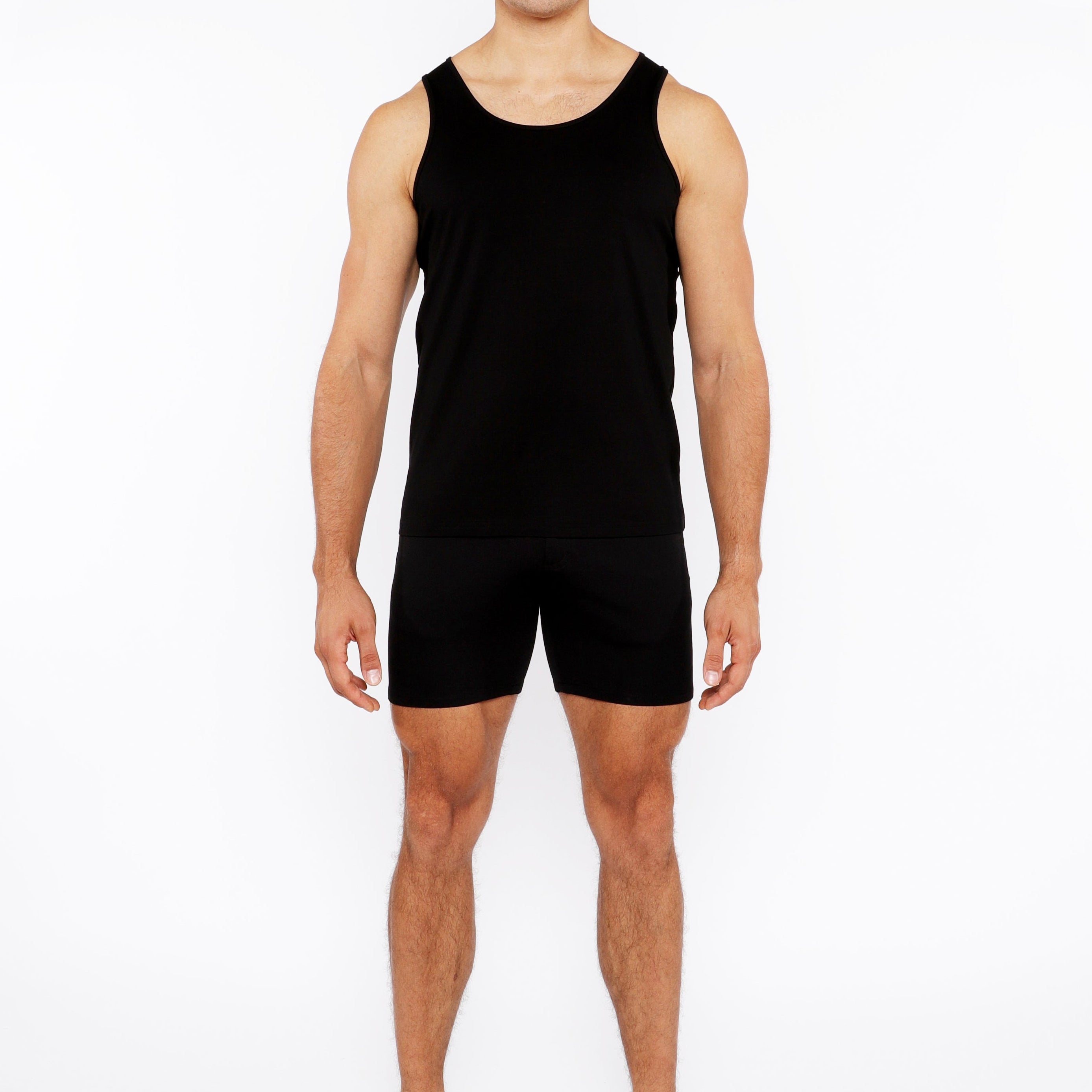 Man wearing a black tank top and shorts on a white background
