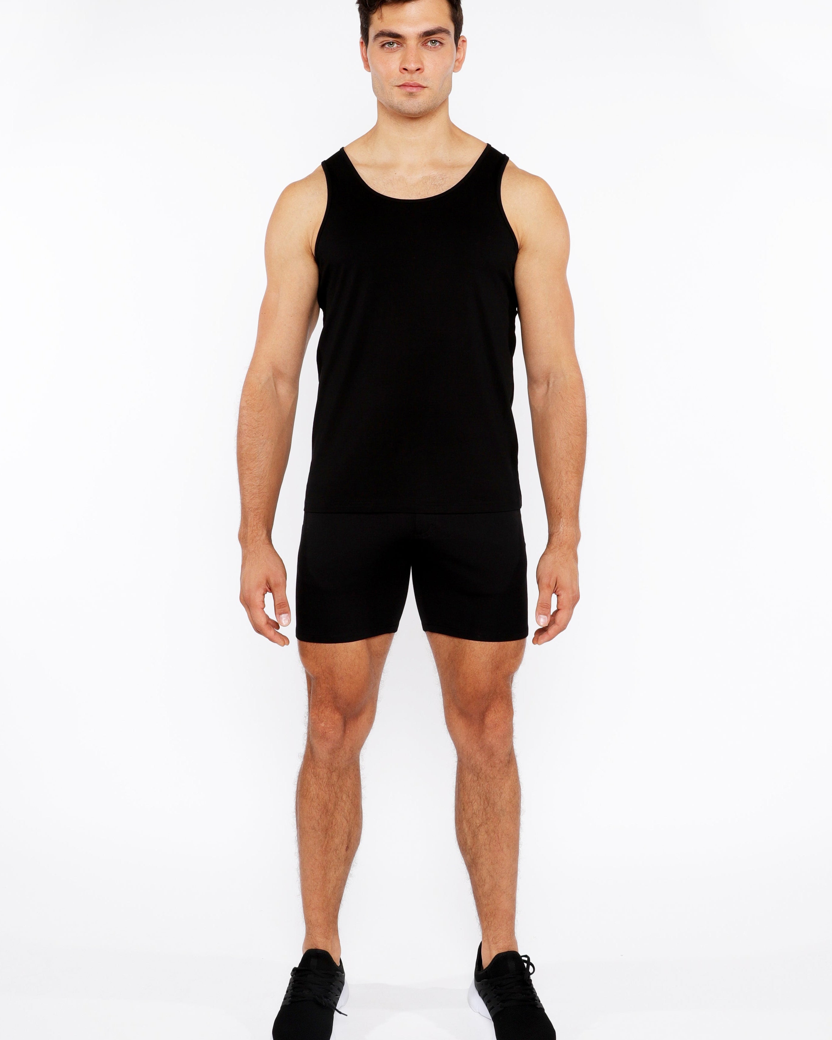 Man wearing a black tank top and shorts on a white background