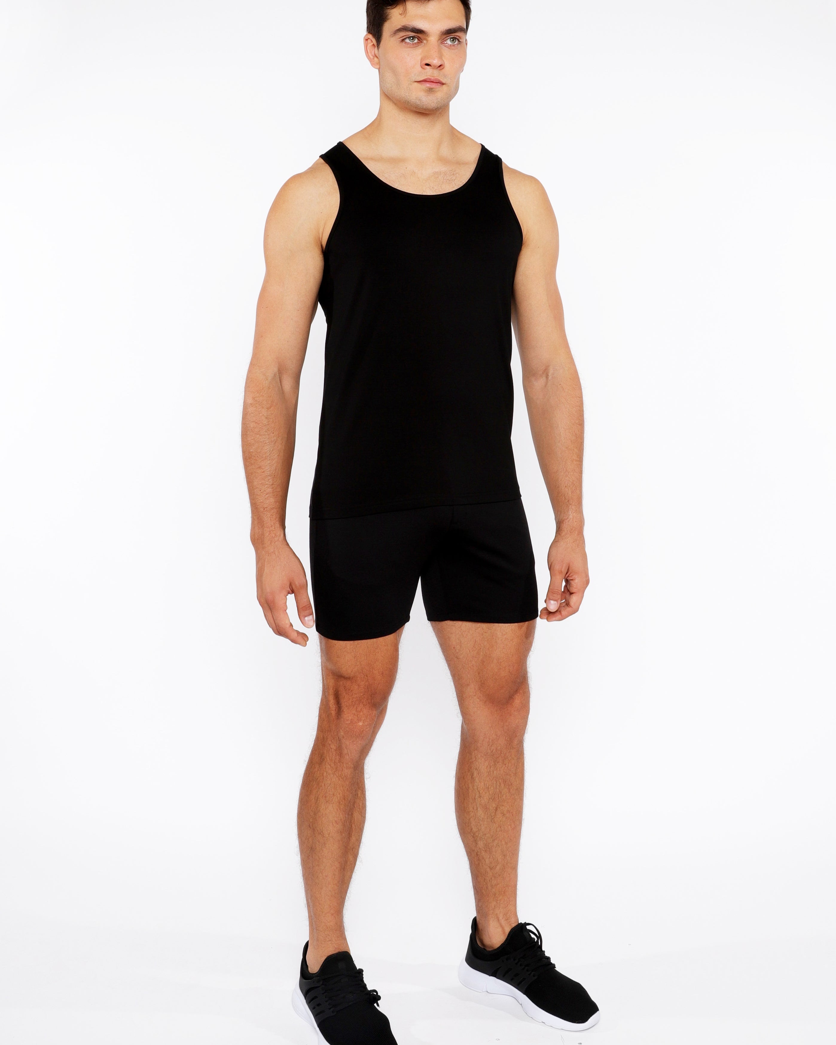 Man wearing a black tank top and shorts on a white background