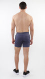 A male model facing away from the camera wearing slate gray mesh stretch performance shorts with a shorter inseam.