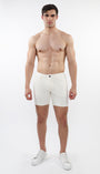 A model wearing white stretch knit shorts with a 5-inch inseam and a slim fit through the thighs and seat.