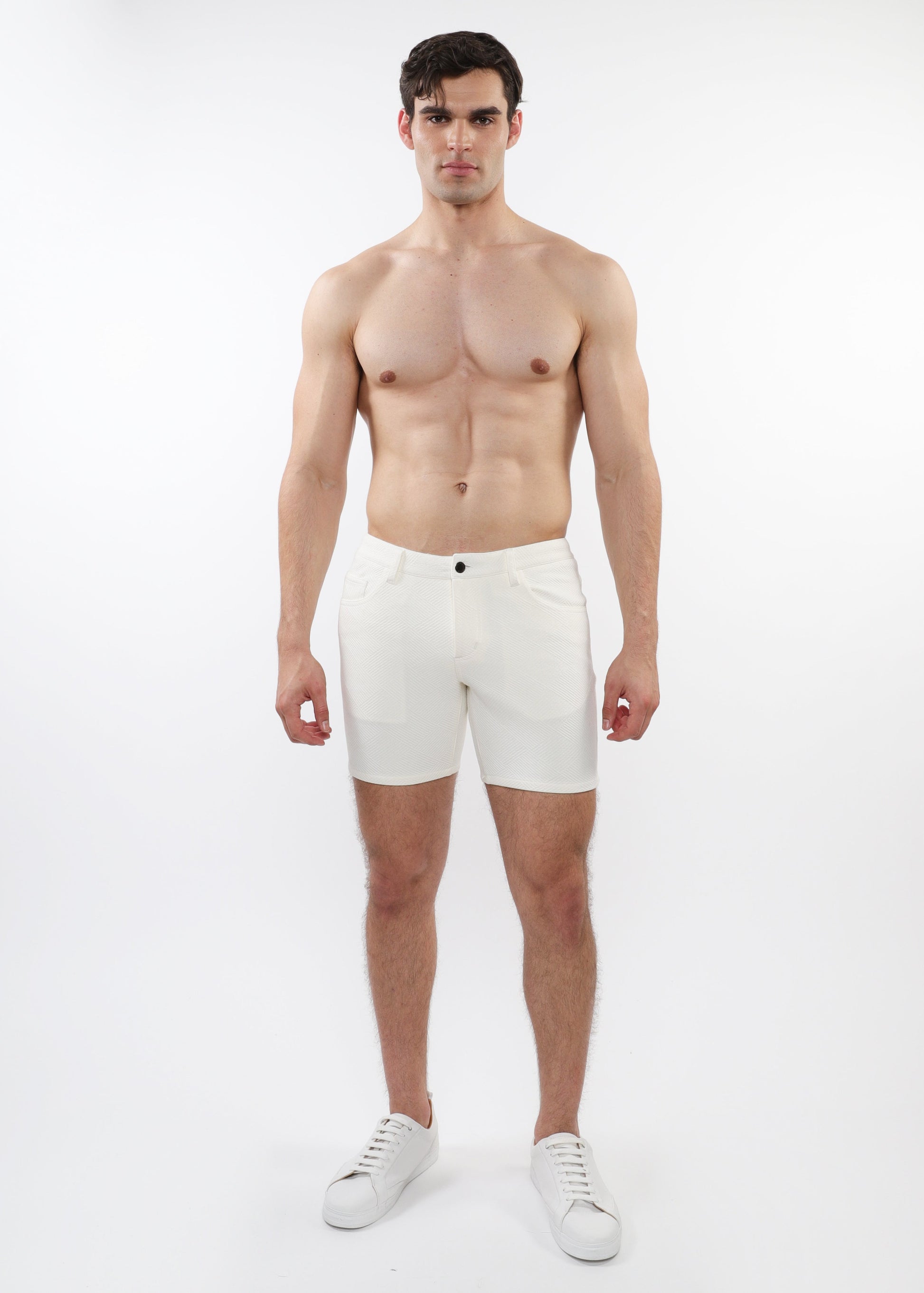 A model wearing white stretch knit shorts with a 5-inch inseam and a slim fit through the thighs and seat.