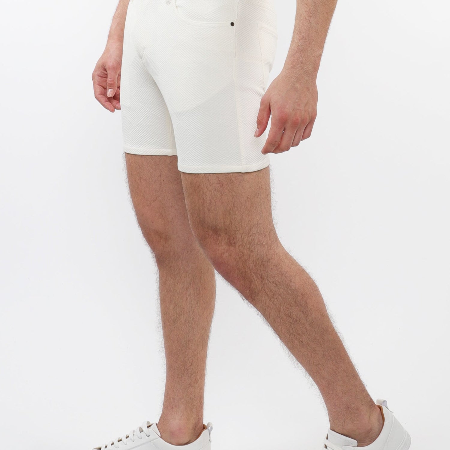 A model wearing white stretch knit shorts with a 5-inch inseam and a slim fit through the thighs and seat.