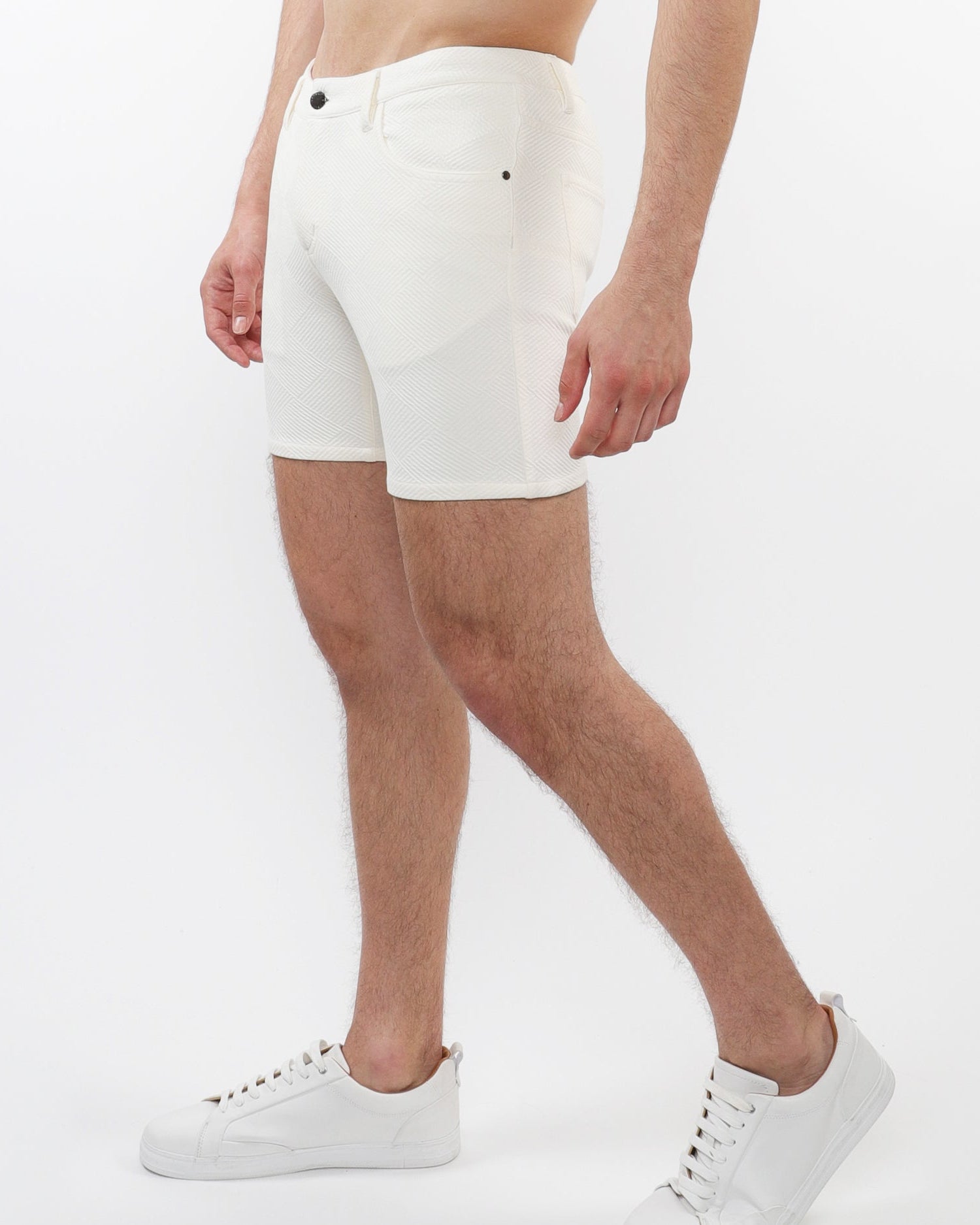 A model wearing white stretch knit shorts with a 5-inch inseam and a slim fit through the thighs and seat.