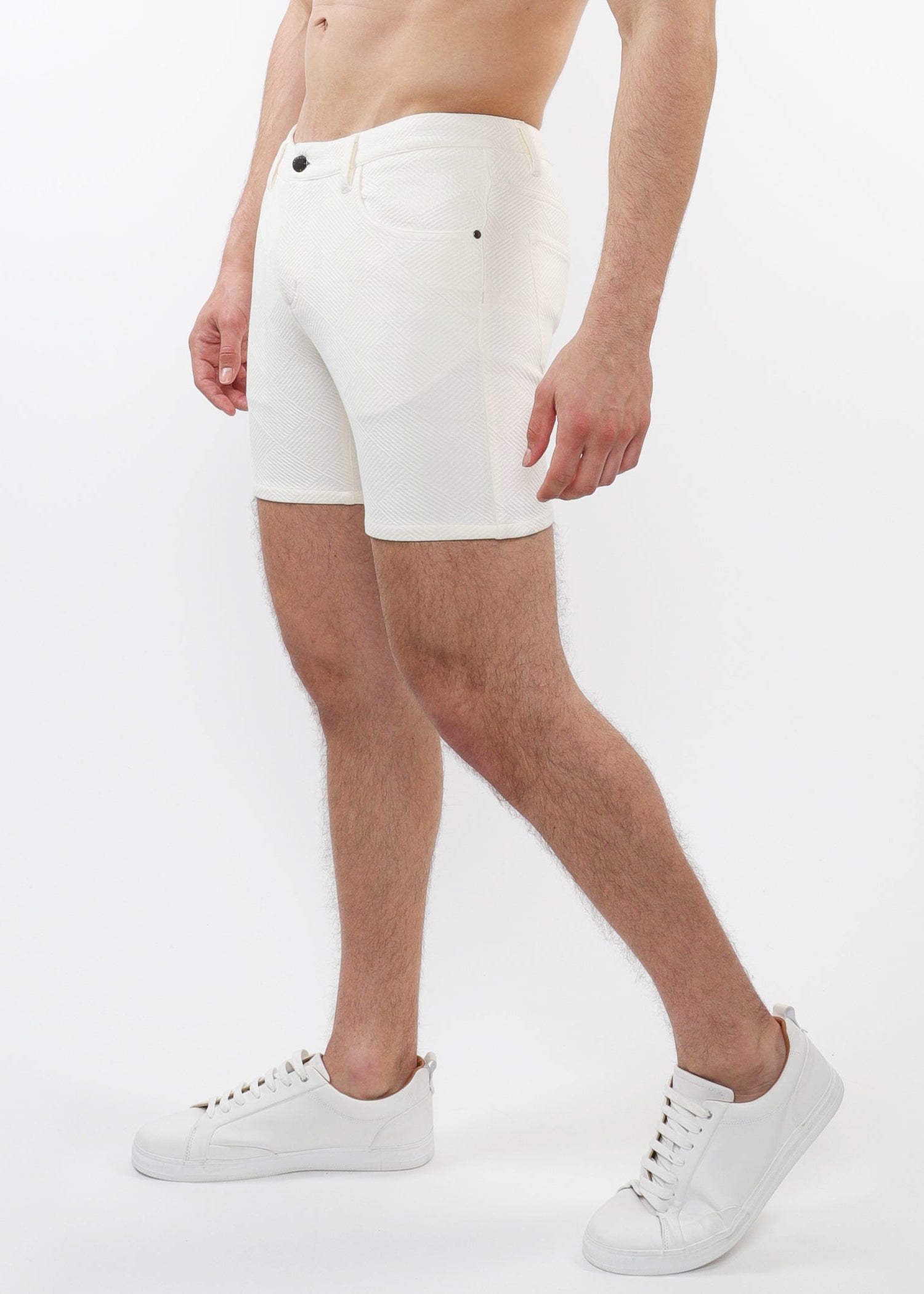 A model wearing white stretch knit shorts with a 5-inch inseam and a slim fit through the thighs and seat.
