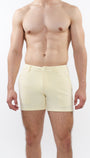 A model wearing cream-colored chino shorts with a slim fit and a 5-inch inseam, paired with white sneakers.
