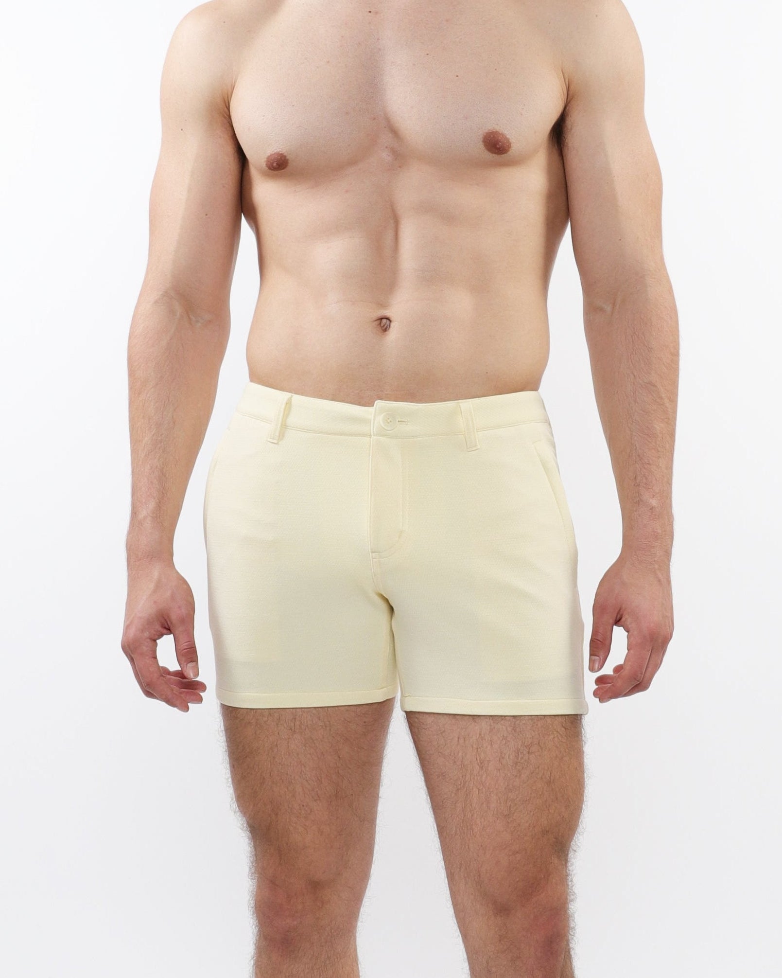 A model wearing cream-colored chino shorts with a slim fit and a 5-inch inseam, paired with white sneakers.