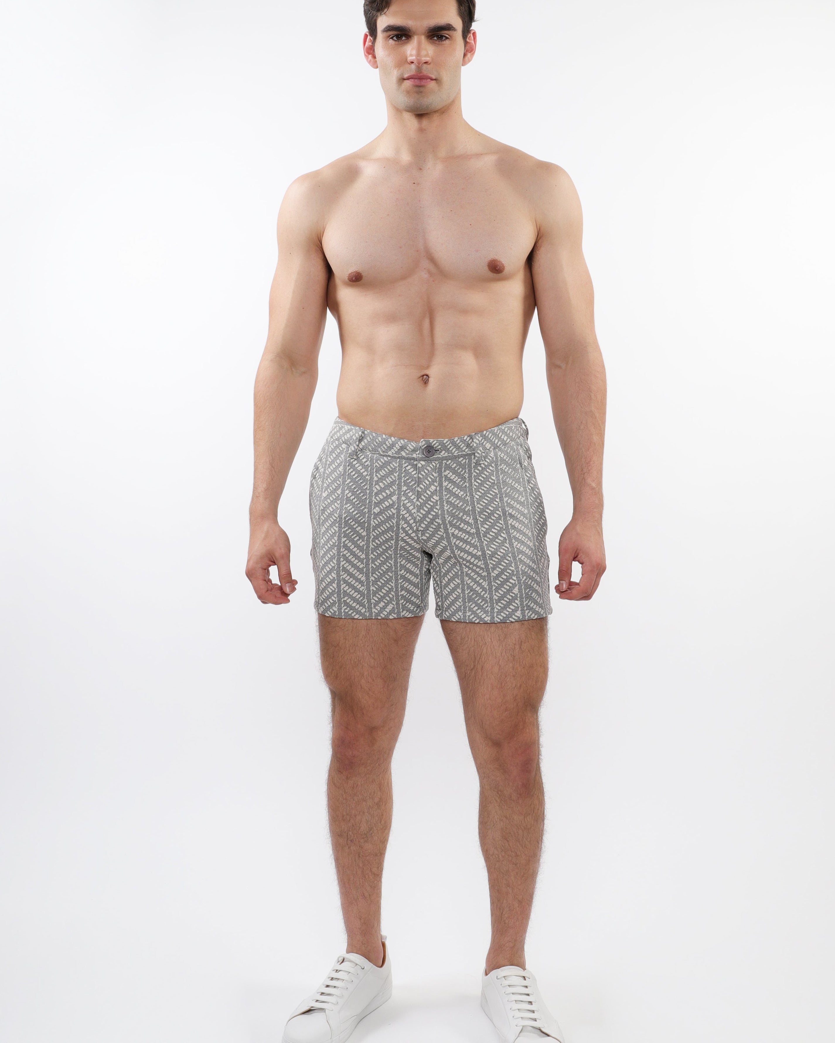 A model wearing ecru and black herringbone patterned chino shorts with zip pockets.