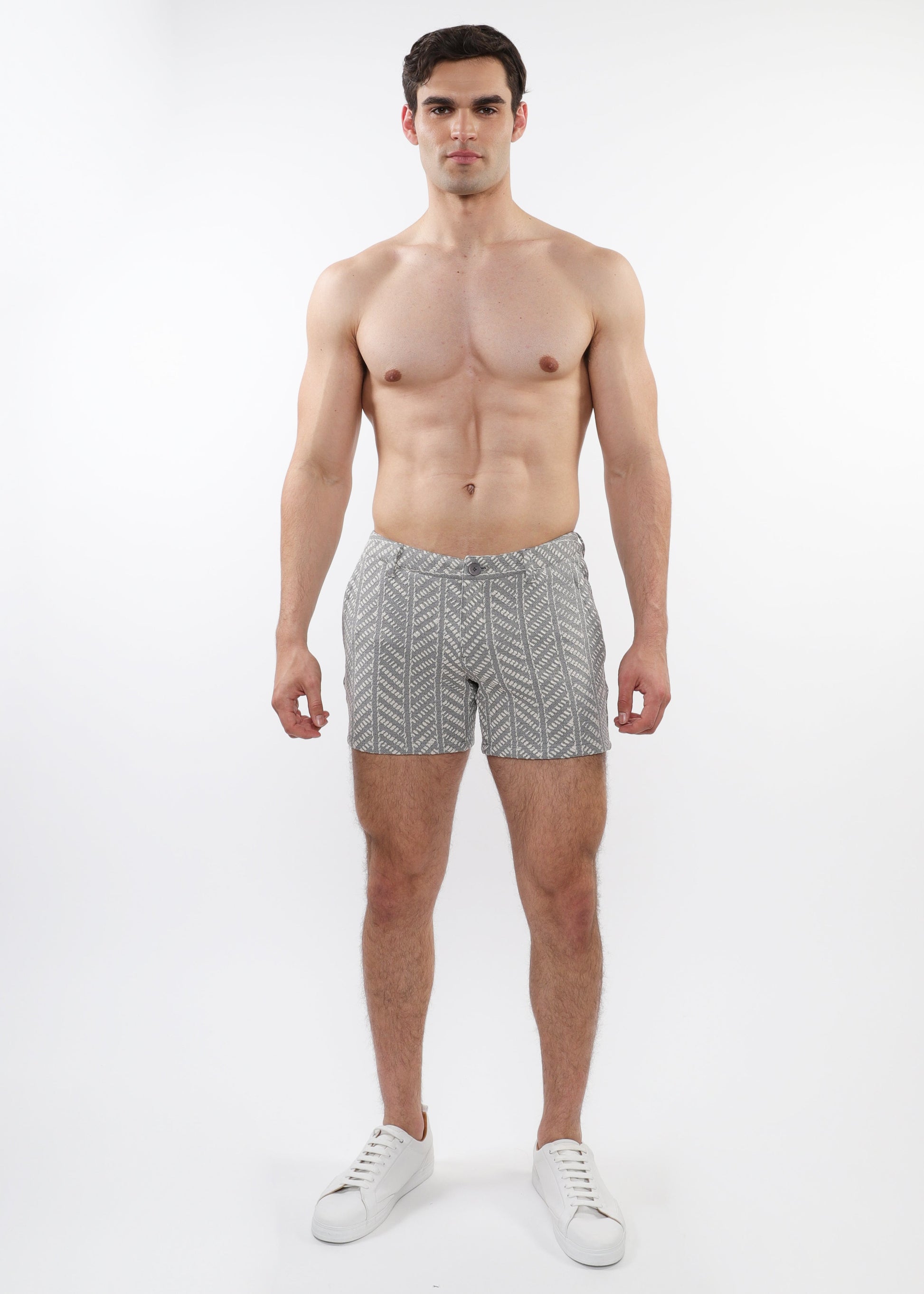 A model wearing ecru and black herringbone patterned chino shorts with zip pockets.
