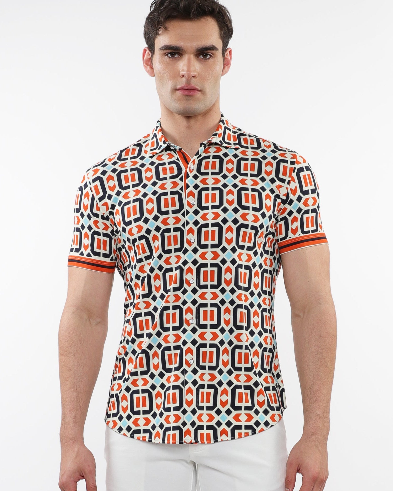 A male model wearing a short sleeve printed knit shirt with a geometric pattern in rust and marine colors over an ecru backdrop, with contrast details on the placket and sleeves.