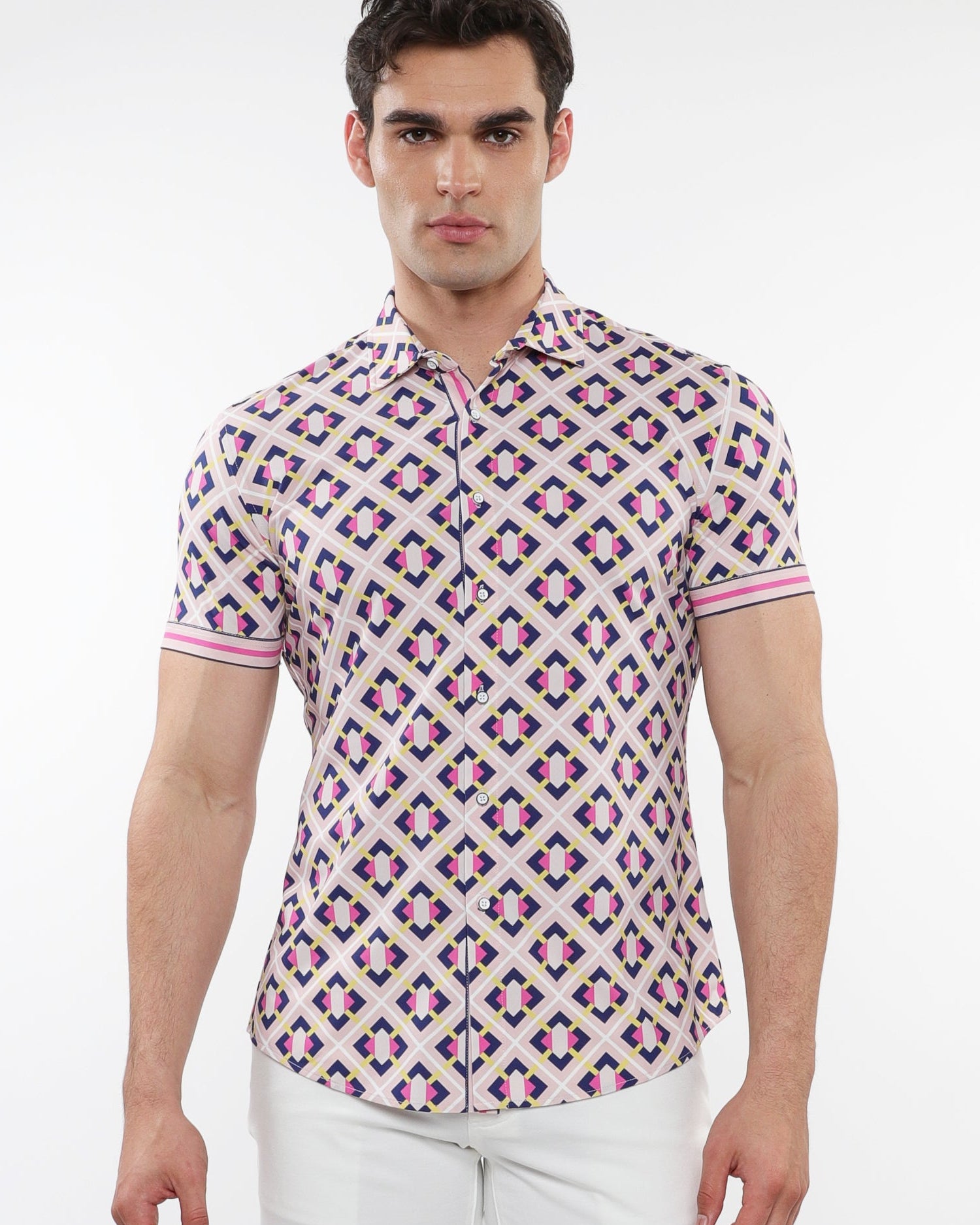 A male model wearing a short sleeve printed knit shirt with a geometric grid pattern in blush and navy colors, with contrast details on the placket and cuffs.