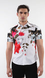 A male model wearing a white short sleeve knit jersey shirt with black, red, and sky blue floral border prints.