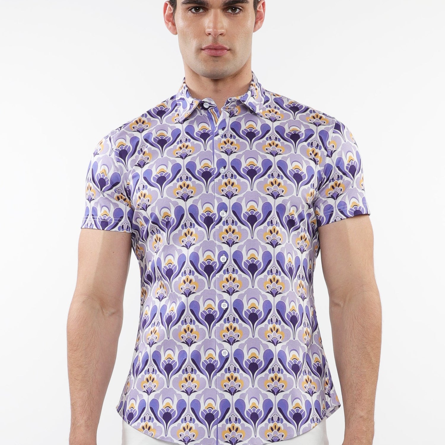 A male model wearing a short sleeve purple and gold floral printed cotton knit jersey shirt with a contrast placket detail and a spread collar.