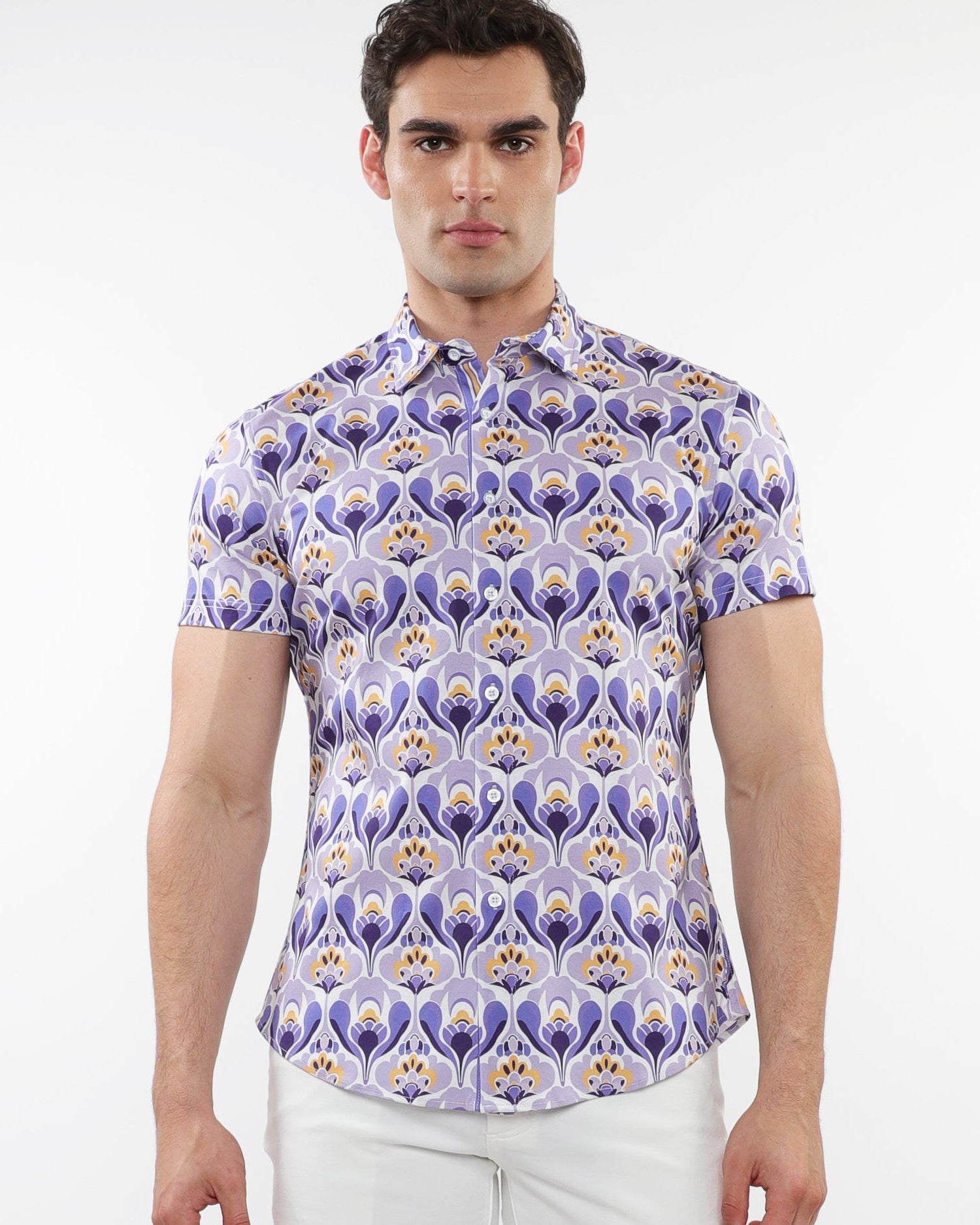A male model wearing a short sleeve purple and gold floral printed cotton knit jersey shirt with a contrast placket detail and a spread collar.
