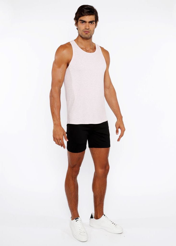 Man wearing a white tank top and black shorts on a white background