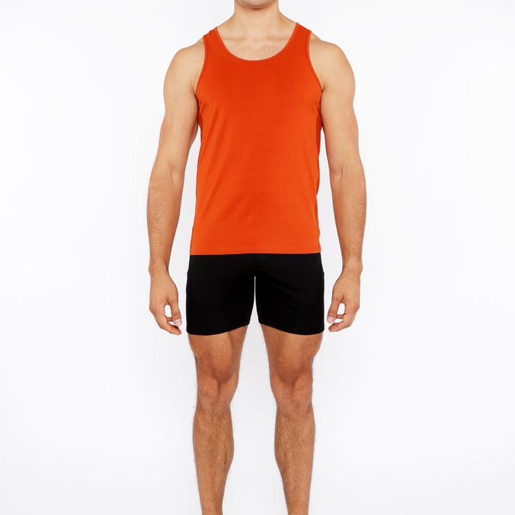 Man wearing an orange tank top and black shorts on a white background