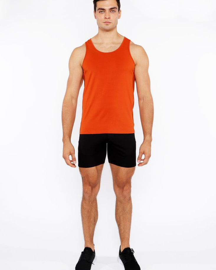 Man wearing an orange tank top and black shorts on a white background