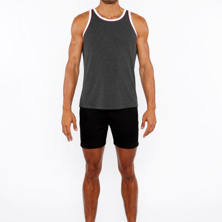 Man wearing a gray tank top and black shorts on a white background
