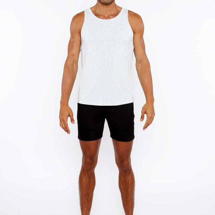 Man wearing a white tank top and black shorts on a white background