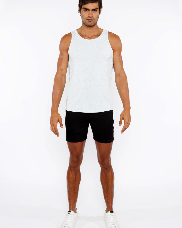 Man wearing a white tank top and black shorts on a white background