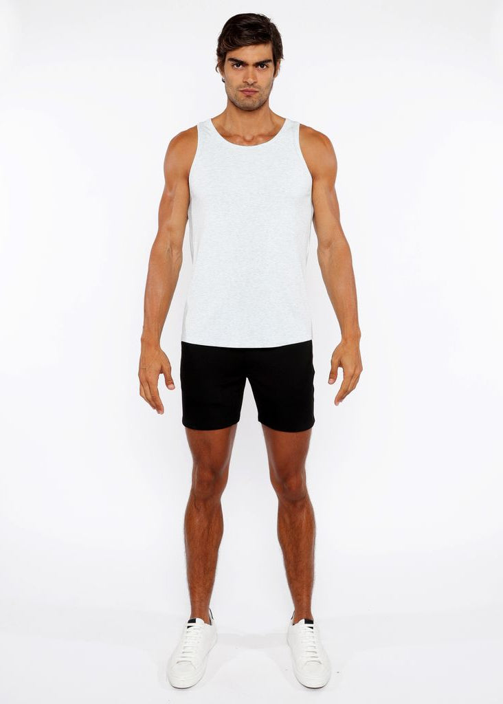 Man wearing a white tank top and black shorts on a white background
