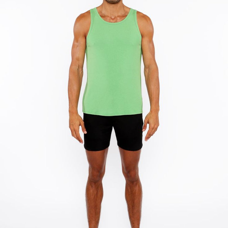 Man wearing a green tank top and black shorts on a white background