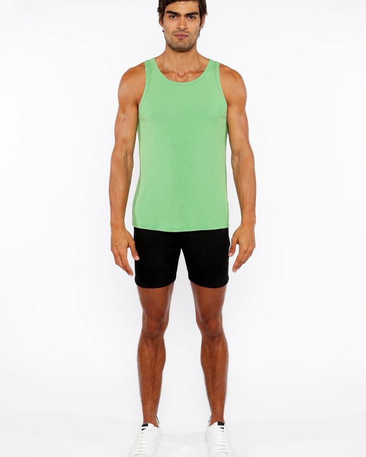 Man wearing a green tank top and black shorts on a white background