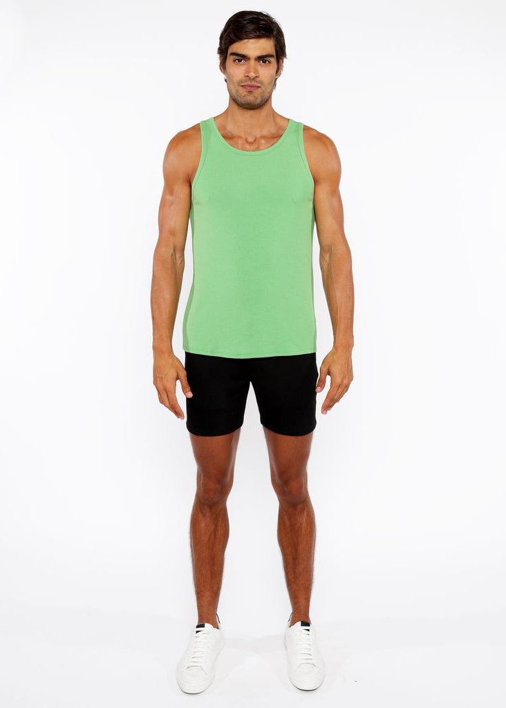 Man wearing a green tank top and black shorts on a white background