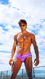 Man in pink swimsuit standing on a rooftop with a blue sky and clouds in the background